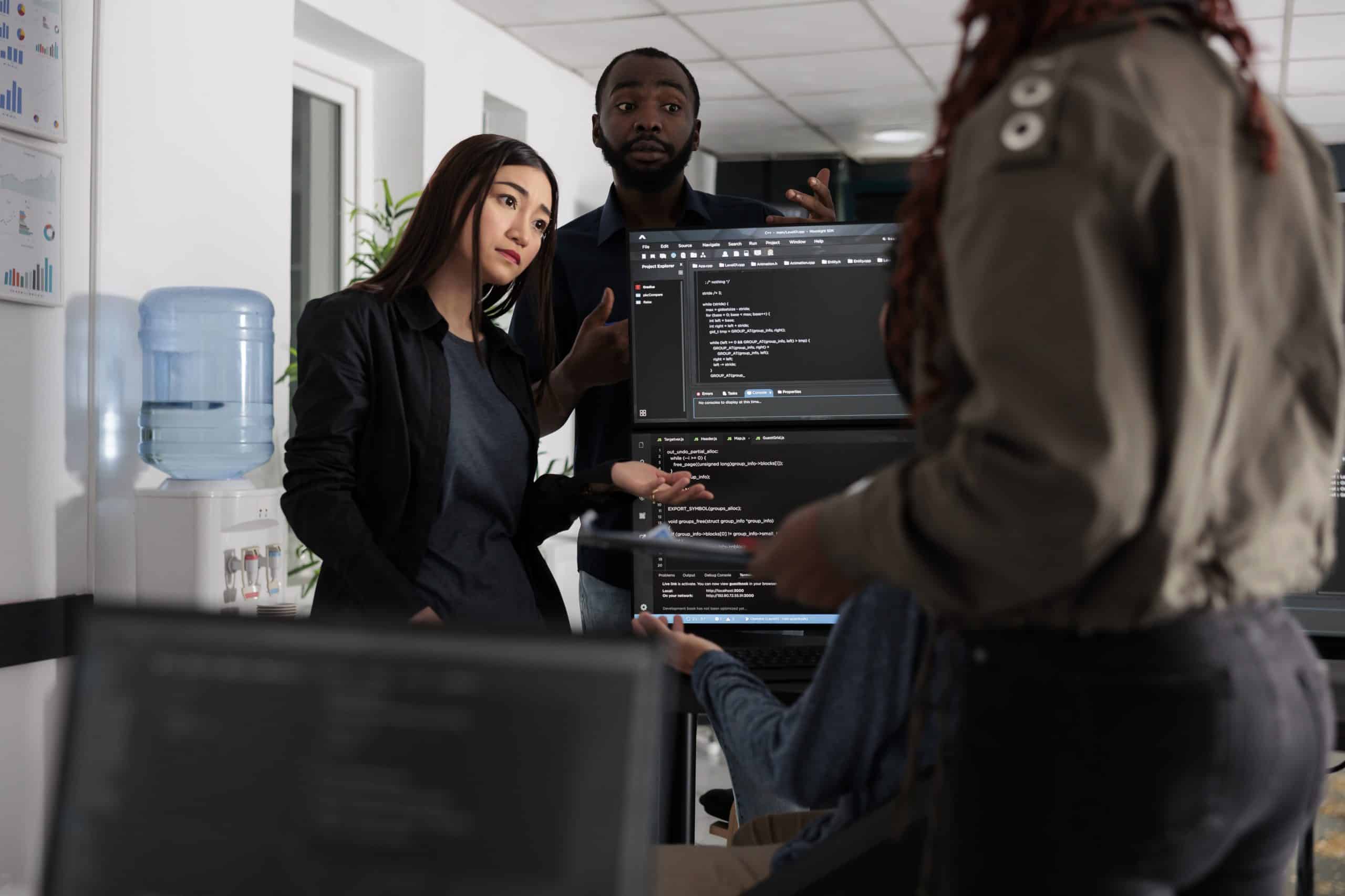Software engineers collaborating on coding project talking about programming algorithm for new cloud computing user interface. Diverse team of web developer running database system code.